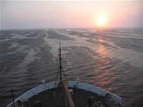 image: Sun low on the horizon, ice patterns on the ocean surface. Photo by C.Ladd